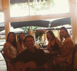 robrowlandmusic holding guitar with some ladies during an event