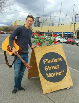 robrowlandmusic holding a guitar during an outdoor event flinders street market